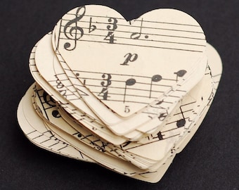 Peut inclure: Une pile de découpes en papier en forme de cœur faites à partir de partitions musicales. Les notes de musique et les clés sont visibles sur le papier.