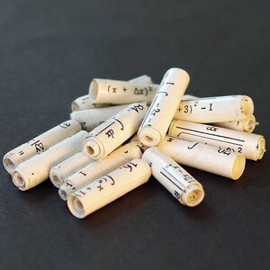 May include: A pile of rolled up paper scraps with handwritten mathematical equations and formulas. The equations include variables like x, delta x, and dx, and numbers like 1, 2, and 3. The paper is white and the ink is black.