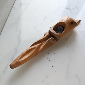 Op de afbeelding: Een houten pijp met een gesneden ontwerp en een metalen gaas aan de bovenkant. De pijp is bruin en heeft een natuurlijke afwerking.