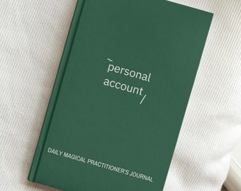 May include: A dark green journal with the text "personal account" and "DAILY MAGICAL PRACTITIONER'S JOURNAL" on the front cover.