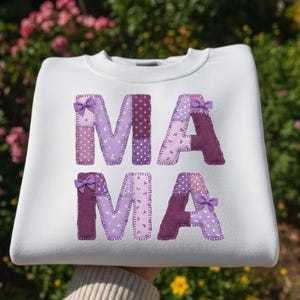 Peut inclure: Sweat-shirt blanc avec le mot "MAMA" appliqué en patchwork de tissu violet. Chaque lettre est ornée d'un petit nœud violet, créant une esthétique charmante et faite à la main. Un haut confortable et élégant.