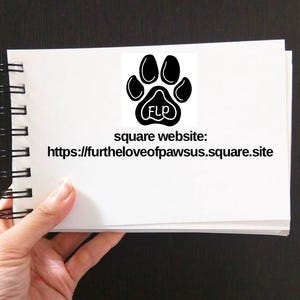May include: A white notebook with a black paw print logo and the text "square website: https://furtheloveofpawsus.square.site" on the front.