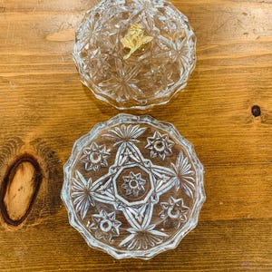 May include: A clear glass trinket box with a starburst pattern. The lid has a gold-coloured accent.