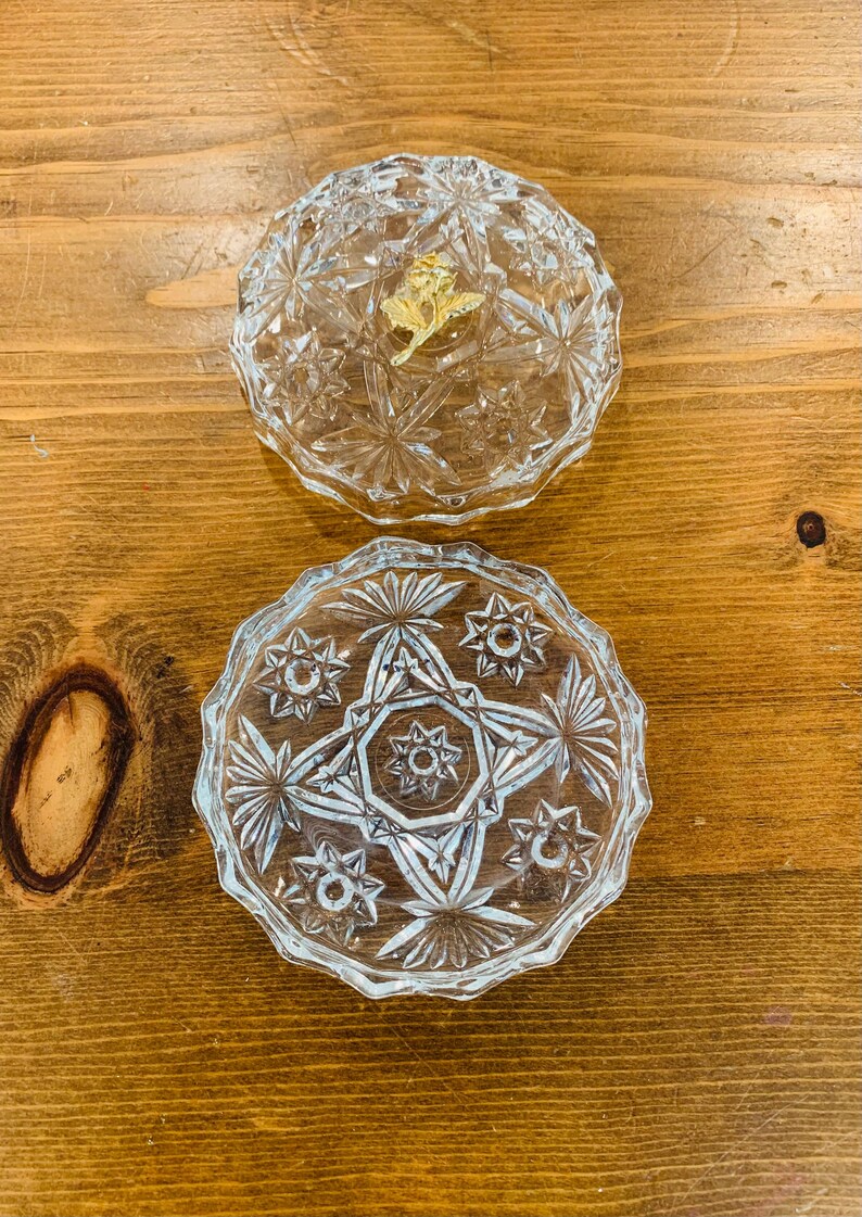 May include: A clear glass trinket box with a starburst pattern. The lid has a gold-coloured accent.