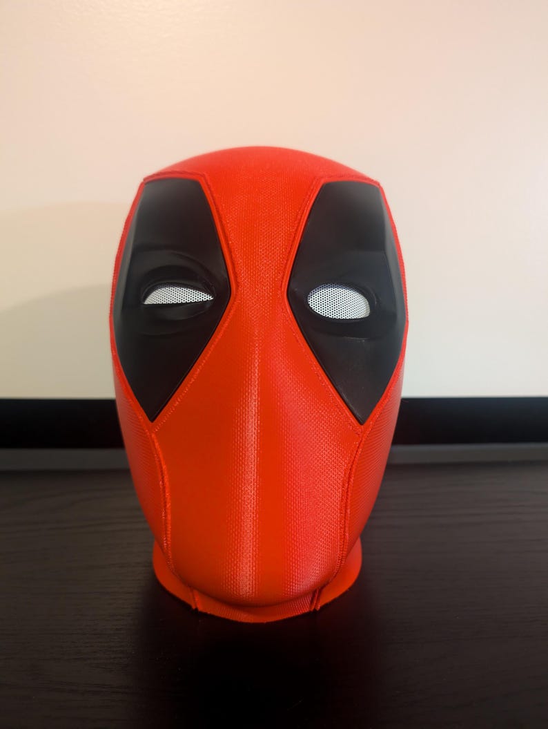 Puede incluir: Una m&aacute;scara de Deadpool roja y negra. La m&aacute;scara es principalmente roja con detalles negros alrededor de los ojos. Las aberturas de los ojos son blancas. La m&aacute;scara es una r&eacute;plica de la m&aacute;scara del personaje de Marvel Comics.