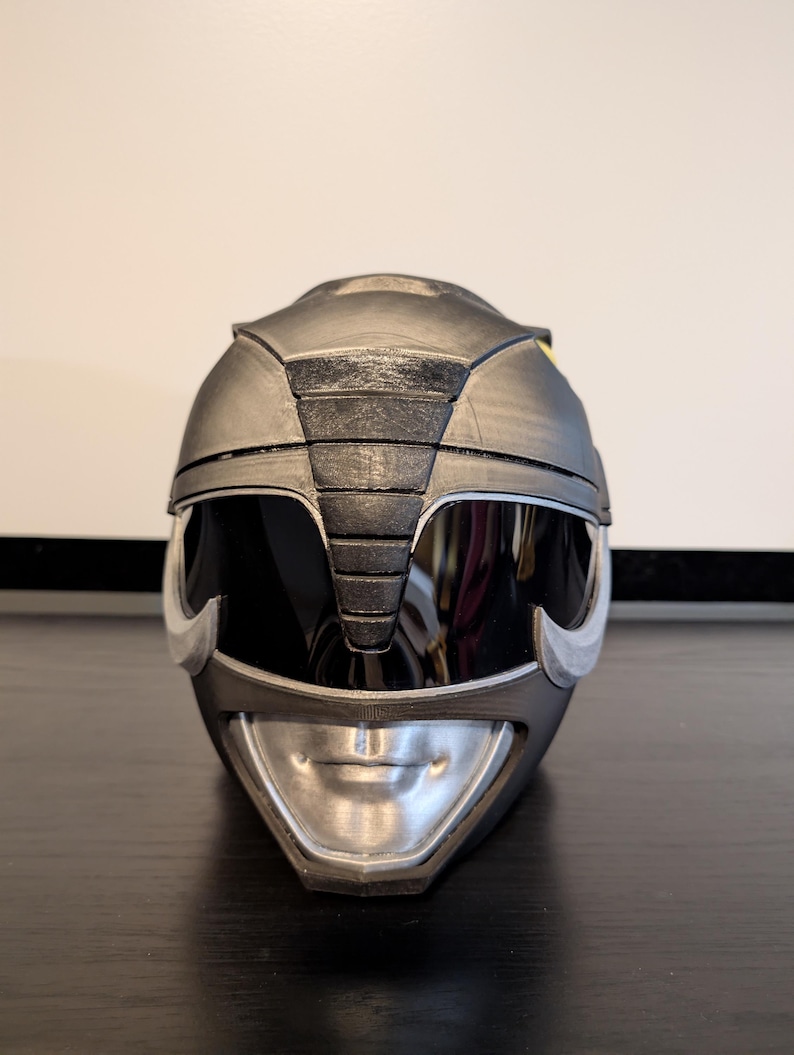 Op de afbeelding: Een zwarte en zilveren Power Rangers helm met een vizier en een gedetailleerd ontwerp.