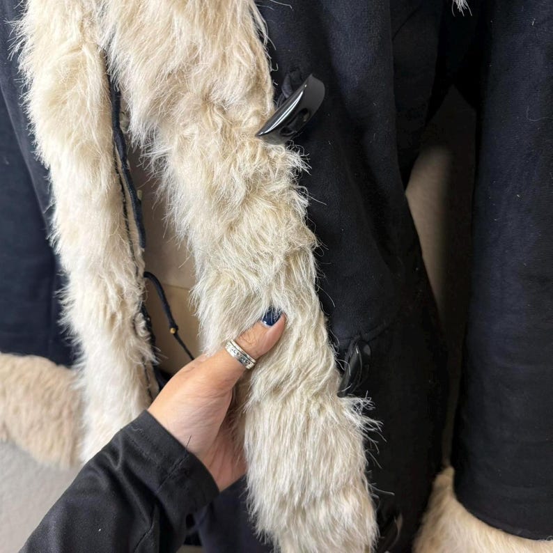 This retro-inspired Black Suede Penny Lane Coat blends luxurious suede with fluffy cream trim for an iconic Afghan look. Perfect for winter layering, cozy evenings, and retro styling, it offers unmatched warmth and texture. The handmade construction ensures durability, softness, and a uniquely vintage feel.
