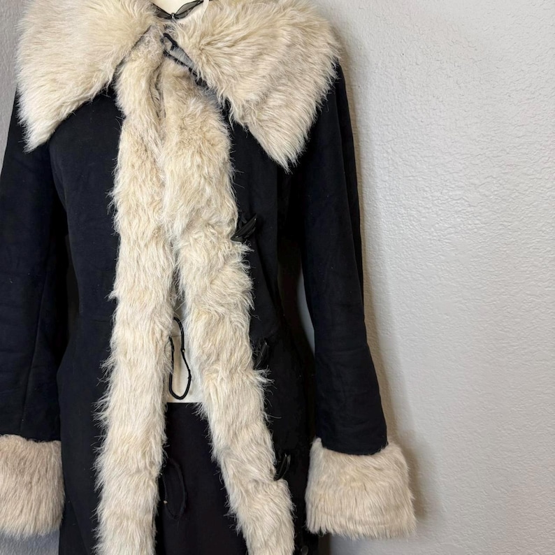 A true 70s classic, this Black Suede Penny Lane Coat showcases shaggy cream trim that highlights the collar, cuffs, and hem beautifully. The long silhouette is flattering and warm, making it ideal for winter days, holiday events, and boho fashion lovers. A timeless handmade piece crafted with attention to detail.