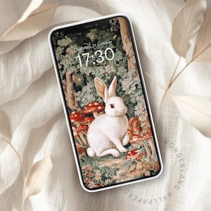 Puede incluir: Un conejo blanco con ojos rojos se sienta en un entorno de bosque con setas y follaje verde. La pantalla del teléfono muestra la hora 17:30 y la fecha jueves 31 de octubre.