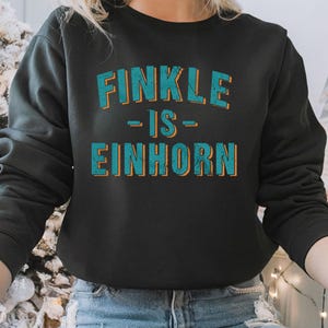 May include: Black sweatshirt with the text "Finkle - is - Einhorn" in teal and orange lettering.