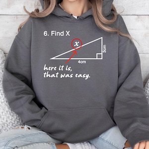 May include: Dark gray hoodie with a graphic of a right triangle and the text "6. Find X" and "here it is, that was easy." The triangle's sides are labeled 3cm and 4cm. A red circle highlights the "x" in the diagram.