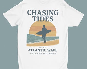 Puede incluir: Camiseta blanca con diseño de playa. El diseño presenta la silueta de un surfista, un sol poniente y olas. El texto incluye "CHASING TIDES" y "ATLANTIC WAVE" con el lema "WAVES. WIND. WILD FREEDOM."