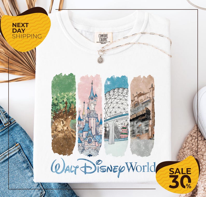 a white t-shirt with a colorful graphic design depicting various Disney landmarks, including the Walt Disney World resort, the Eiffel Tower, and the Hollywood Tower. The t-shirt is displayed on a white background, and there are yellow and black sale tags visible, indicating a 30% discount on the item.