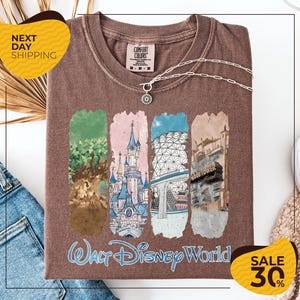 a brown t-shirt with a graphic design depicting various Disney World landmarks, including the Walt Disney World resort and the Wood Tower. The t-shirt is displayed on a white background, and there are yellow and black sale signs indicating a 30% discount.