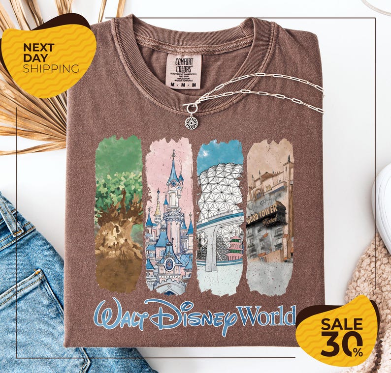 a brown t-shirt with a graphic design depicting various Disney World landmarks, including the Walt Disney World resort and the Wood Tower. The t-shirt is displayed on a white background, and there are yellow and black sale signs indicating a 30% discount.