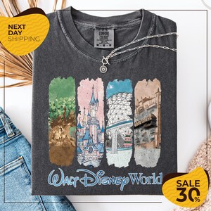 a gray t-shirt with a graphic design depicting various Disney World landmarks, including the Walt Disney World resort, the Wood Tower, and the Epcot Pavilion. The t-shirt is displayed on a white background, and there are two yellow sale signs indicating a 30% discount on the item.