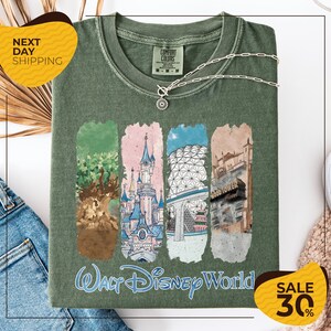 a green t-shirt with a graphic design of various Disney World landmarks, including the Walt Disney World resort, the Epcot International Space Needle, and the Hollywood Hills. The t-shirt is displayed on a white background, and there are yellow and black sale signs indicating a 30% discount on the item.