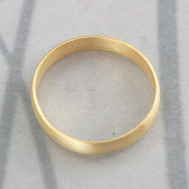 May include: A simple gold wedding band with a smooth, brushed finish.