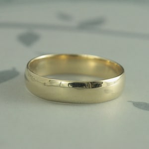May include: A simple gold wedding band with a smooth, polished finish.
