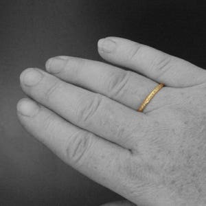 May include: A thin gold band ring with a textured surface.