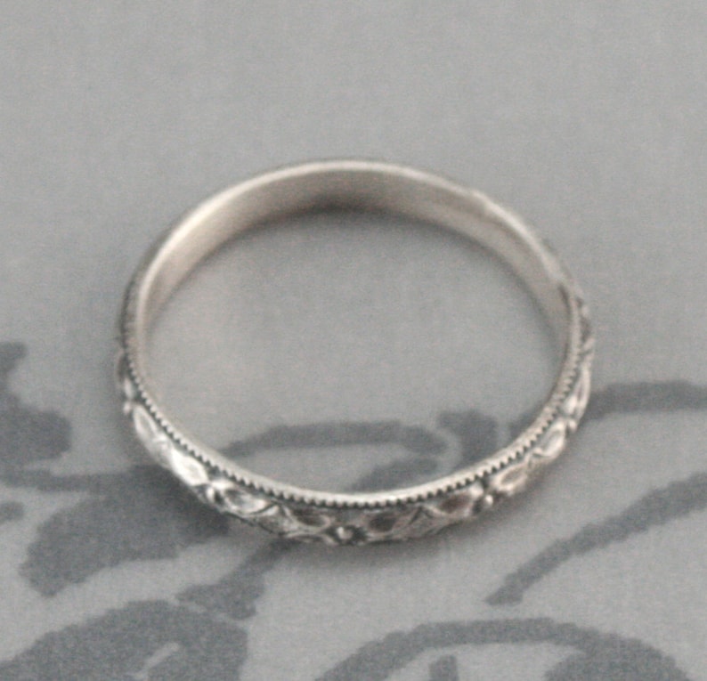 May include: A silver band ring with a delicate floral design.