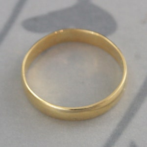 May include: A simple gold wedding band with a smooth, polished finish.