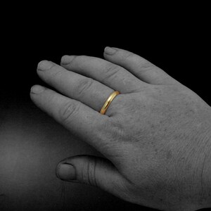 May include: A plain gold wedding band worn on a finger.