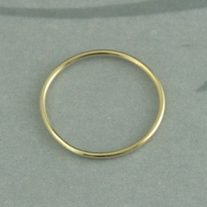 May include: A simple gold band ring.