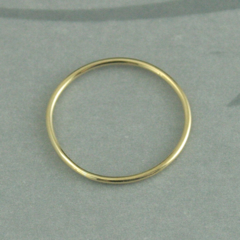 May include: A simple gold band ring.