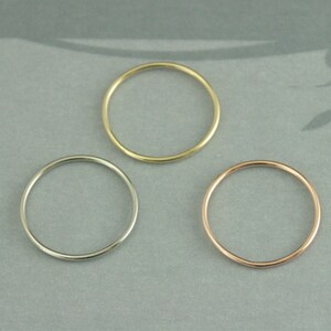 May include: Three thin metal rings in different colors: gold, silver, and rose gold. The rings are simple and delicate, perfect for stacking or wearing alone.