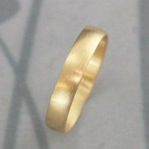 May include: A simple gold wedding band with a brushed finish.