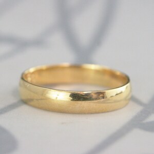 May include: A simple gold wedding band with a smooth, polished finish.