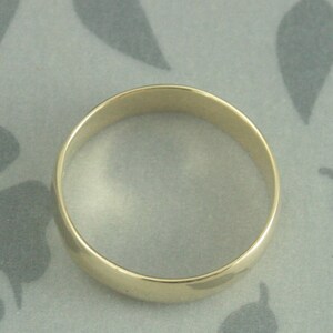 May include: A simple gold wedding band with a rounded edge.