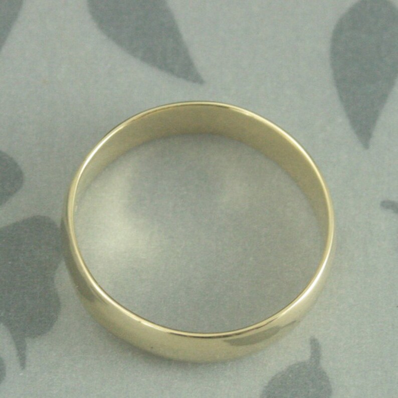 May include: A simple gold wedding band with a rounded edge.