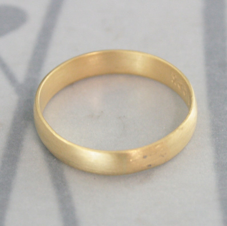 May include: A simple gold wedding band with a brushed finish.