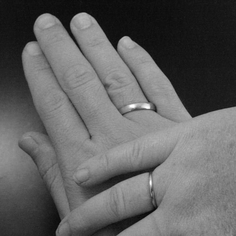 Pu&ograve; includere: Due mani con fedi nuziali sui loro anulari. Le mani sono intrecciate, con una mano sopra l'altra.