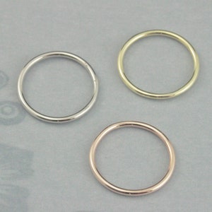 Puede incluir: Tres anillos simples y finos de metal en plata, oro y oro rosa.