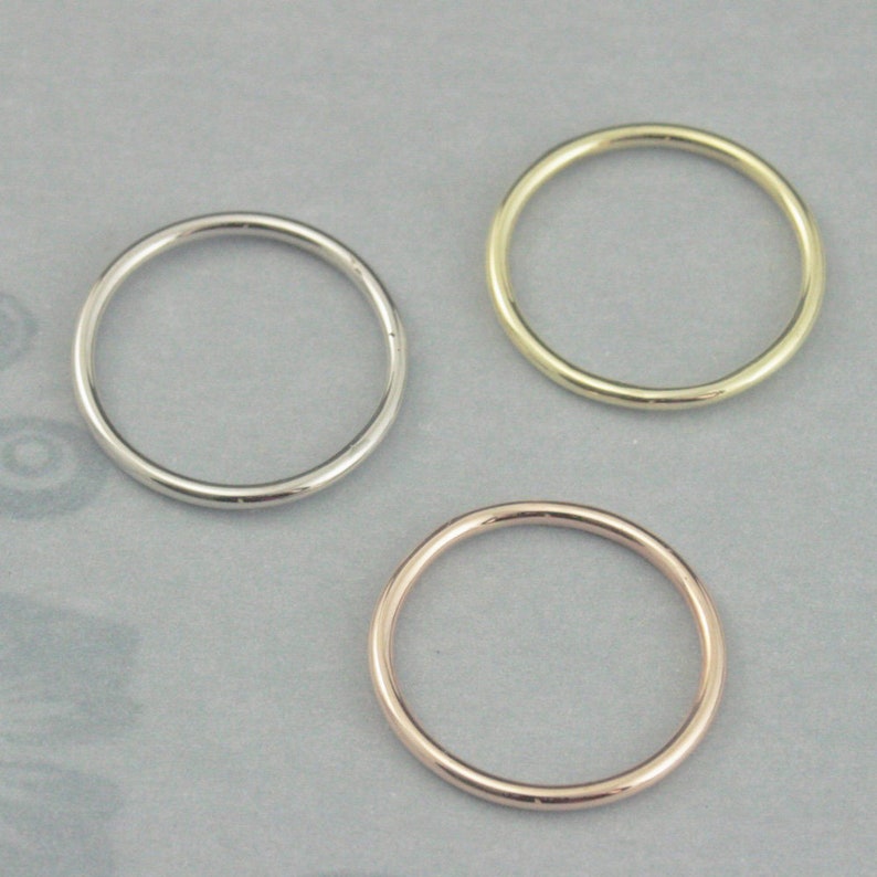 Puede incluir: Tres anillos simples y finos de metal en plata, oro y oro rosa.