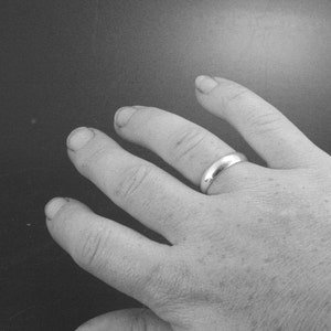 Puede incluir: Primer plano de una mano con una alianza de plata.