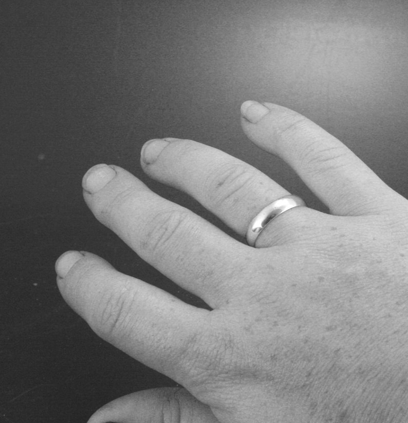 Puede incluir: Primer plano de una mano con una alianza de plata.