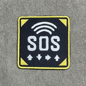 May include: Square patch with a black background and yellow border. The patch features the white letters "SOS" beneath three white curved lines, and four white arrows. The patch is likely an embroidered patch.