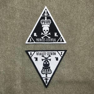 Może przedstawiać: Biały ceramiczny kubek z czarnym uchwytem i napisem "But First, Coffee" pogrubioną, czarną czcionką. Kubek jest umieszczony na rozmytym tle, sugerującym przytulne otoczenie. Kubek ma około 10 cm wysokości.