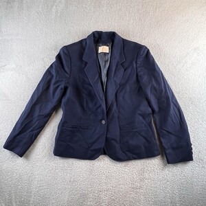 May include: A navy blue blazer with a single-button closure and two front pockets. The blazer has a classic notched lapel and long sleeves. The garment is made of a solid, dark blue fabric.