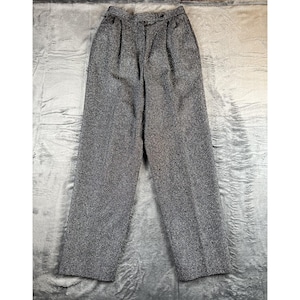 May include: Gray tweed trousers with a high waist and pleats. The pants have a button and zipper closure and a classic, wide-leg design. The fabric has a textured appearance.