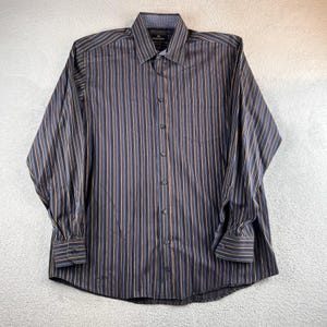 May include: A long-sleeved button-down shirt with vertical stripes in navy blue, tan, and light blue. The shirt has a classic collar and a chest pocket. The cuffs and collar lining feature a patterned design.