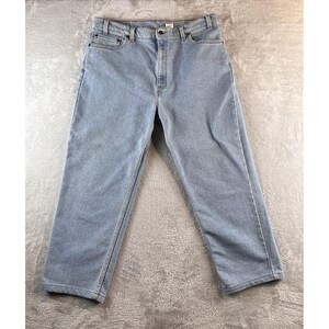 May include: Light blue denim jeans with a classic five-pocket design. The jeans have a straight leg cut and a button and zipper closure. The fabric appears to be a medium weight denim.
