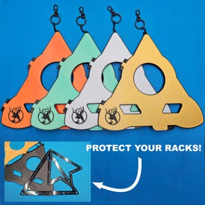 May include: Four triangular rack protectors in orange, light green, white, and gold, each featuring a black deer logo and a metal keychain attachment. An inset shows a black triangular frame with the text PROTECT YOUR RACKS! and an arrow.
