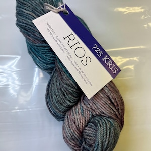 Könnte beinhalten: Ein Knäuel teal- und rosafarbenes Garn mit der Aufschrift "RIOS 725 KRIS" und den Details "WORSTED, Approx. 210 yd (192 m), 100 g, 18-22 sts - 4 Inches, NS: US 7-9 OR 4.5-5.5 mm, 100% Superwash Merino Wool."