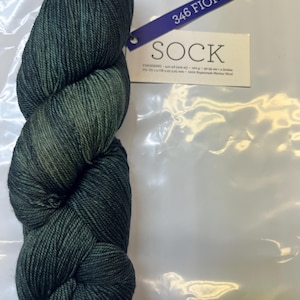 Può includere: Un gomitolo di filato verde scuro etichettato "346 Fiona SOCK" con le parole "FINGERING - 100% Superwash Merino Wool" sull'etichetta.