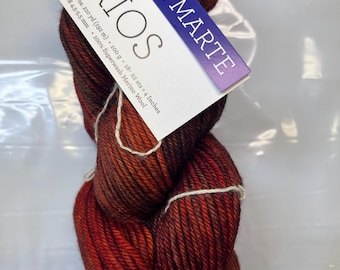 May include: A skein of Rios 121 Marte yarn in a gradient of red and brown. The yarn is 100% superwash merino wool and is approximately 210 yards (192 meters) long.